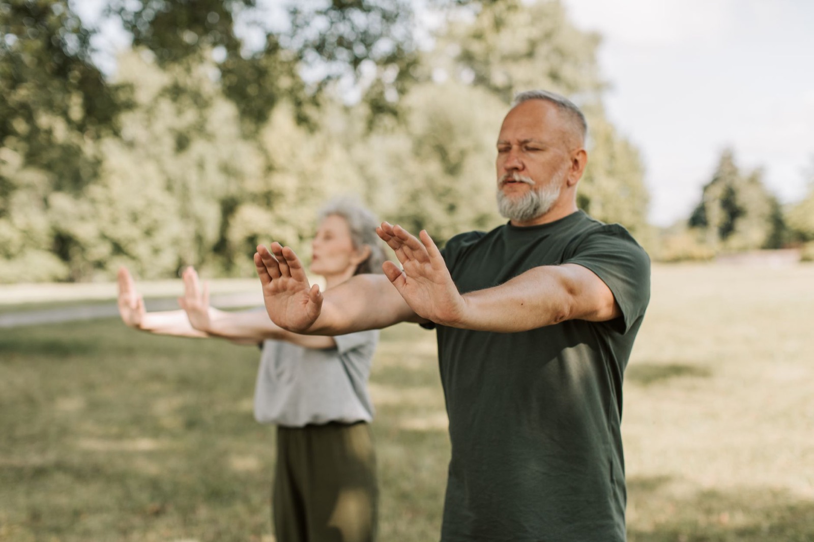 Twee 50-plussers doen tai chi in een park